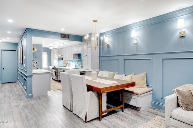 dining area with a chandelier, light hardwood / wood-style floors, and sink