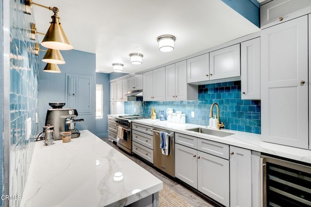 kitchen with stainless steel appliances, decorative light fixtures, wine cooler, light stone countertops, and sink