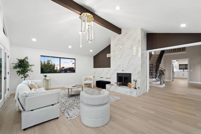 living room featuring a fireplace, light hardwood / wood-style floors, and vaulted ceiling with beams