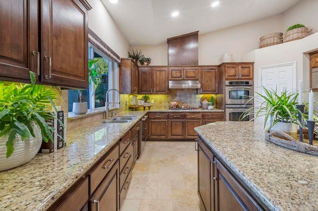 kitchen with light stone countertops, stainless steel appliances, decorative backsplash, and sink