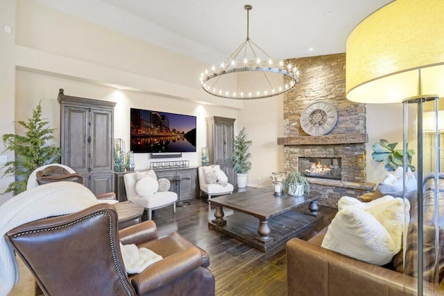 living room featuring dark wood-type flooring, a fireplace, and a notable chandelier