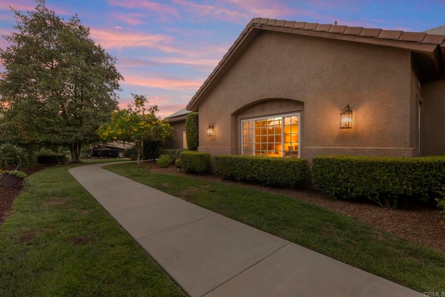 property exterior at dusk with a lawn