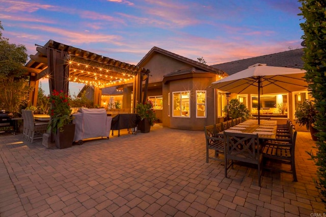 patio terrace at dusk with grilling area and a pergola