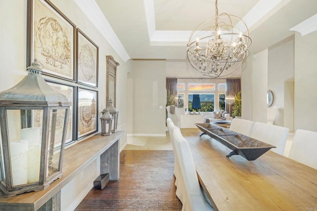 dining space with a raised ceiling, wood-type flooring, crown molding, and a chandelier