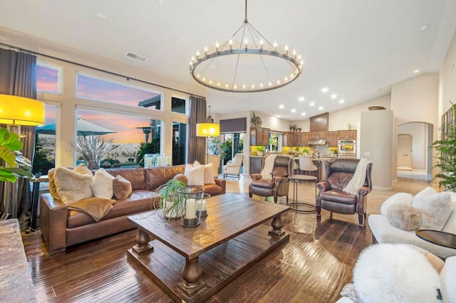 living room with hardwood / wood-style floors, a notable chandelier, and vaulted ceiling