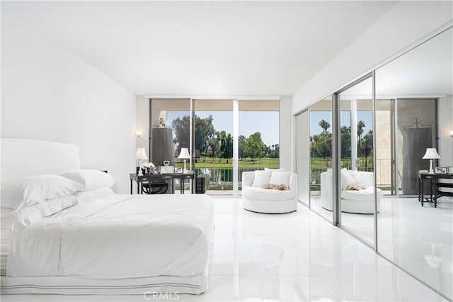 bedroom with access to outside, floor to ceiling windows, and a water view