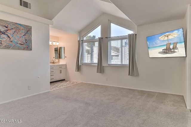 unfurnished bedroom with light colored carpet, lofted ceiling, connected bathroom, and sink