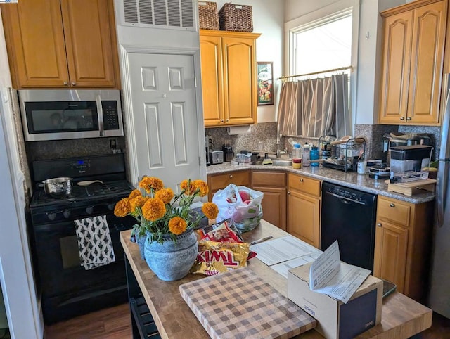 kitchen featuring backsplash, light stone counters, and black appliances