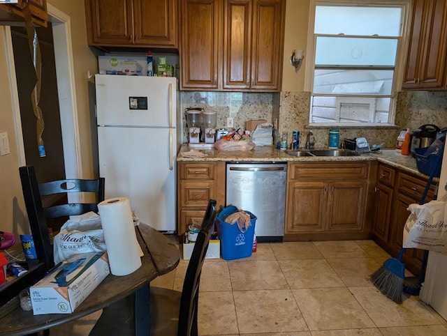 kitchen with dishwasher, white refrigerator, tasteful backsplash, sink, and light stone counters