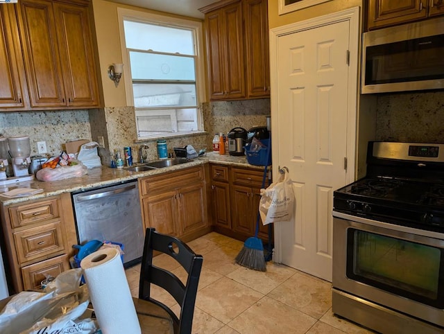 kitchen featuring light tile patterned floors, stainless steel appliances, decorative backsplash, light stone counters, and sink