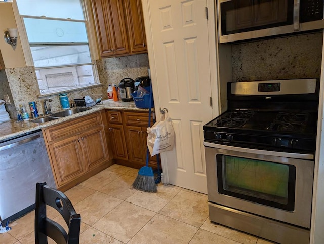 kitchen featuring decorative backsplash, appliances with stainless steel finishes, sink, and light stone counters