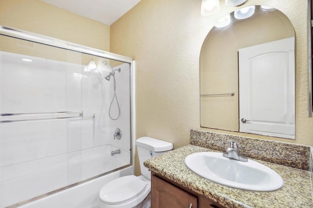 full bathroom with bath / shower combo with glass door, toilet, and vanity