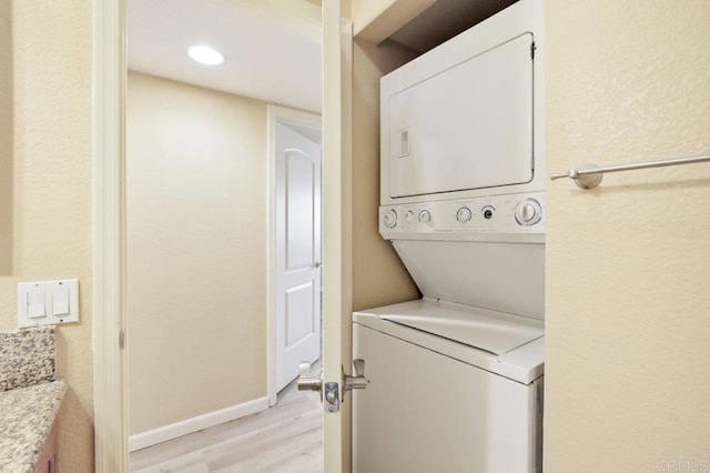 laundry room featuring light wood-type flooring and stacked washer / dryer