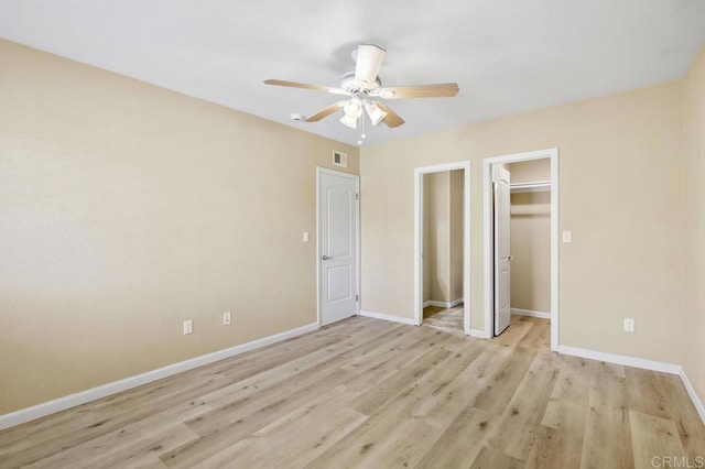 unfurnished bedroom featuring a spacious closet, ceiling fan, a closet, and light hardwood / wood-style floors