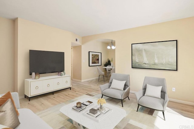 living room with light wood-type flooring and a notable chandelier