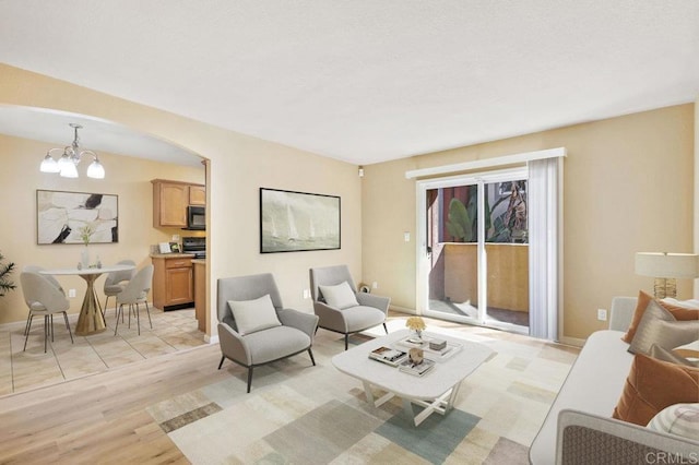 living room with light hardwood / wood-style floors and a notable chandelier