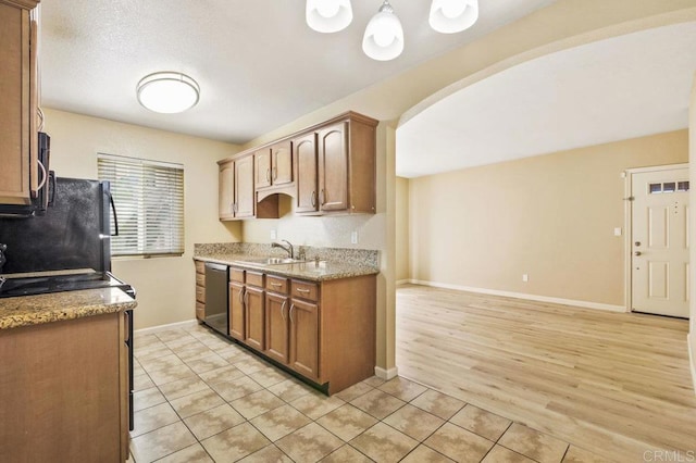 kitchen featuring decorative light fixtures, stainless steel dishwasher, black refrigerator, sink, and light tile patterned floors