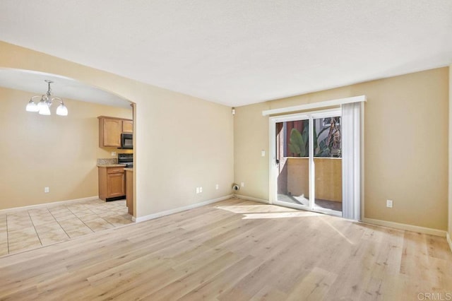 spare room featuring a chandelier and light hardwood / wood-style floors