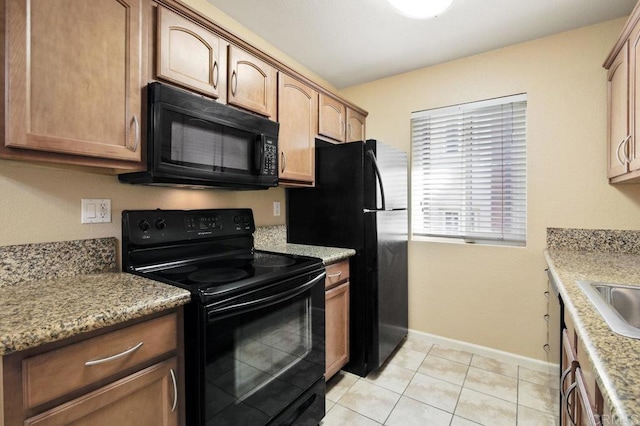 kitchen featuring light stone counters, light tile patterned floors, and black appliances