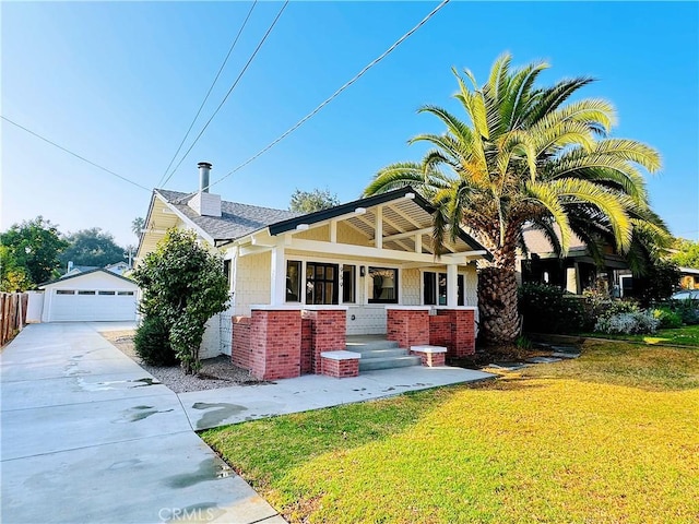 view of front facade with a front lawn, a garage, a porch, and an outdoor structure