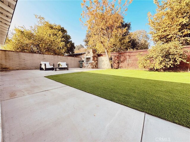 view of yard featuring an outdoor fireplace and a patio