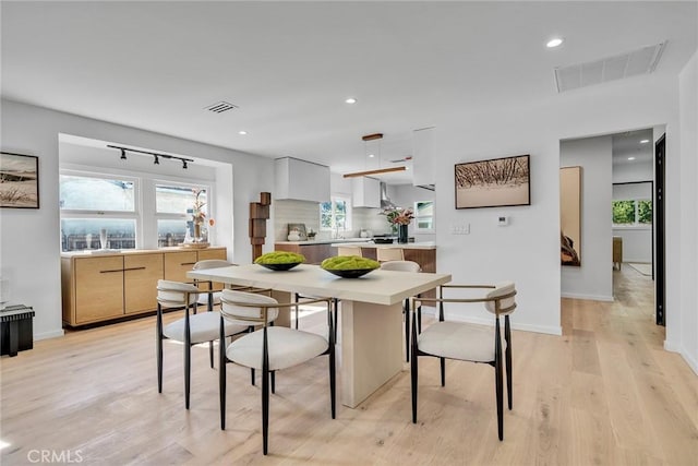 kitchen featuring white cabinets, a kitchen bar, light hardwood / wood-style flooring, and dishwasher