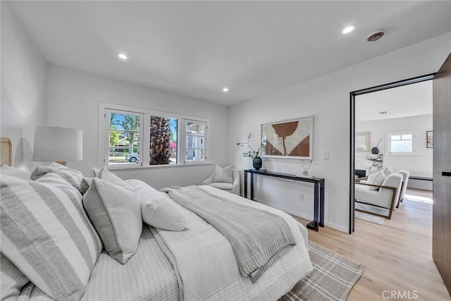 bedroom featuring a baseboard heating unit, multiple windows, and light hardwood / wood-style flooring