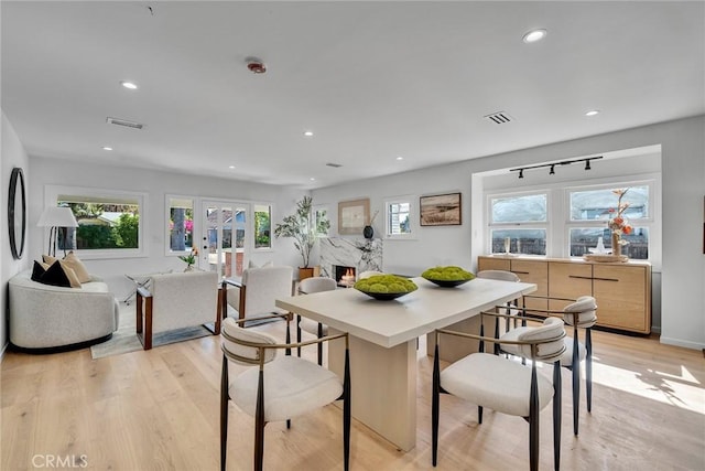 dining area featuring a fireplace, french doors, and light wood-type flooring