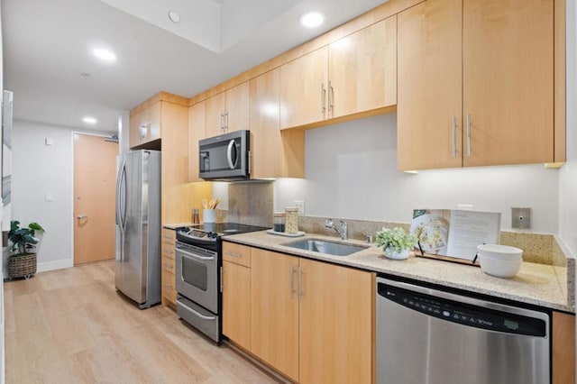 kitchen with light wood-type flooring, appliances with stainless steel finishes, sink, and light brown cabinets