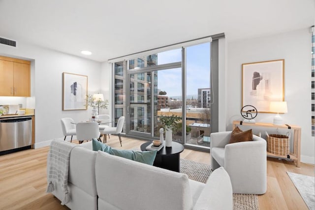 living room with expansive windows and light hardwood / wood-style flooring