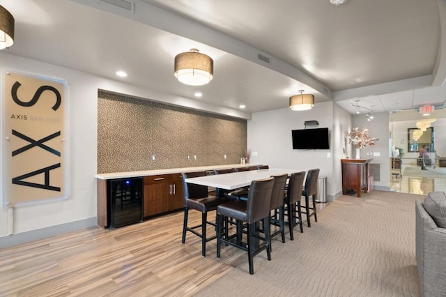 dining area with beverage cooler and light hardwood / wood-style flooring