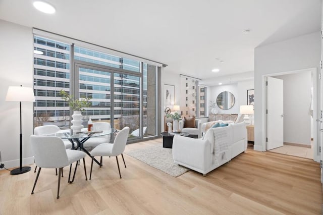 living room with a wall of windows and light hardwood / wood-style flooring