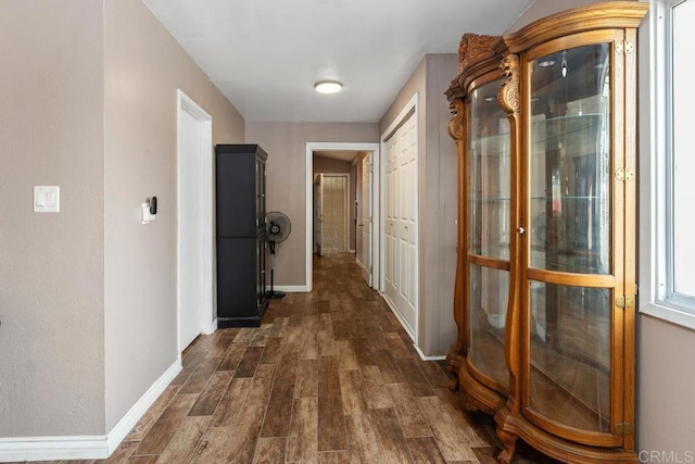 hallway with dark wood-style floors and baseboards