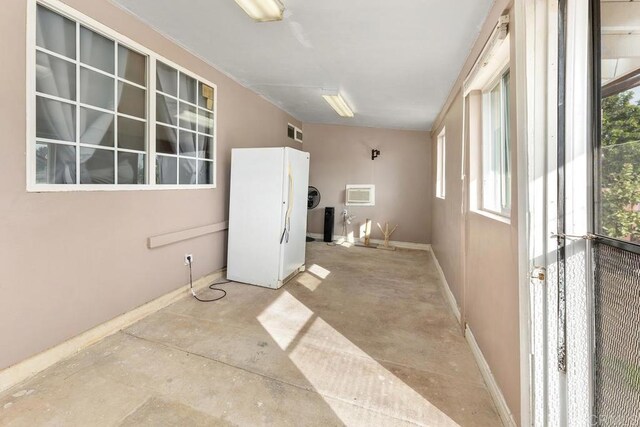 empty room with a wealth of natural light, a wall unit AC, visible vents, and unfinished concrete floors