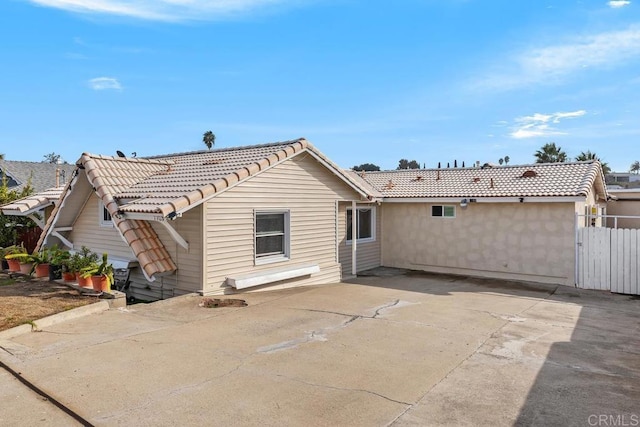 back of property with a tile roof and fence