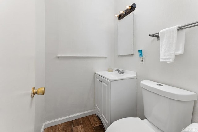 bathroom featuring baseboards, vanity, toilet, and wood finished floors