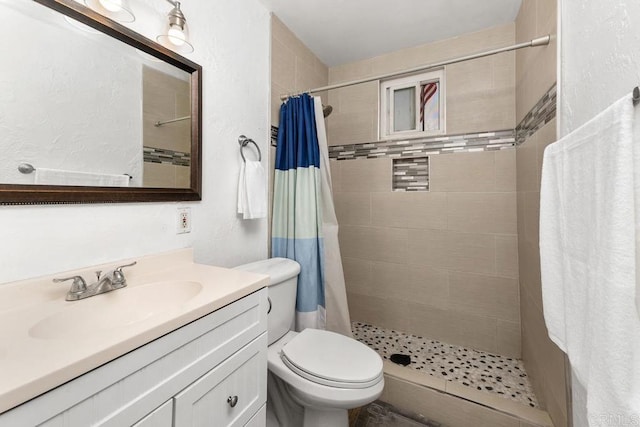 full bath featuring a textured wall, toilet, a shower stall, and vanity