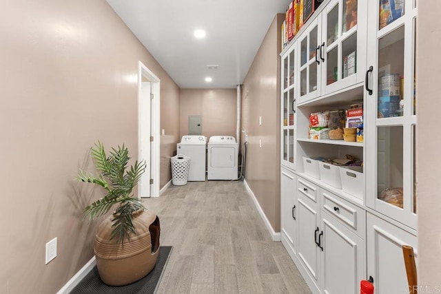 clothes washing area with laundry area, baseboards, light wood-style floors, and washing machine and clothes dryer