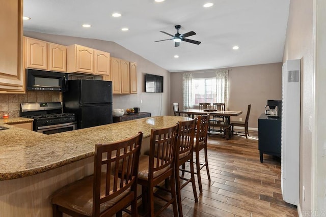 kitchen featuring black appliances, vaulted ceiling, dark wood finished floors, and light brown cabinetry