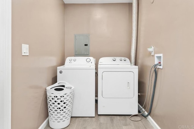 washroom with laundry area, baseboards, light wood-type flooring, electric panel, and washing machine and clothes dryer