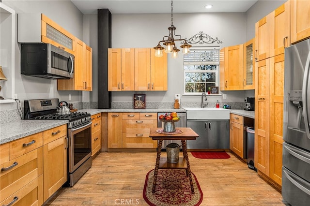 kitchen featuring sink, light hardwood / wood-style flooring, appliances with stainless steel finishes, light stone countertops, and a chandelier