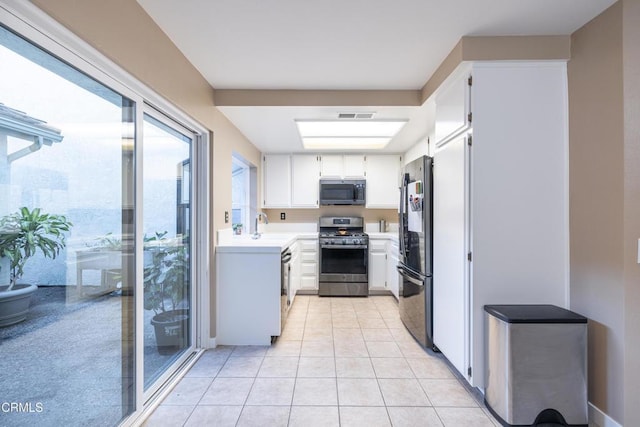 kitchen featuring light tile patterned floors, sink, stainless steel appliances, and white cabinetry