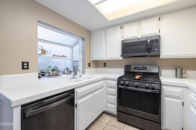 kitchen featuring light tile patterned flooring, stainless steel appliances, white cabinetry, and sink