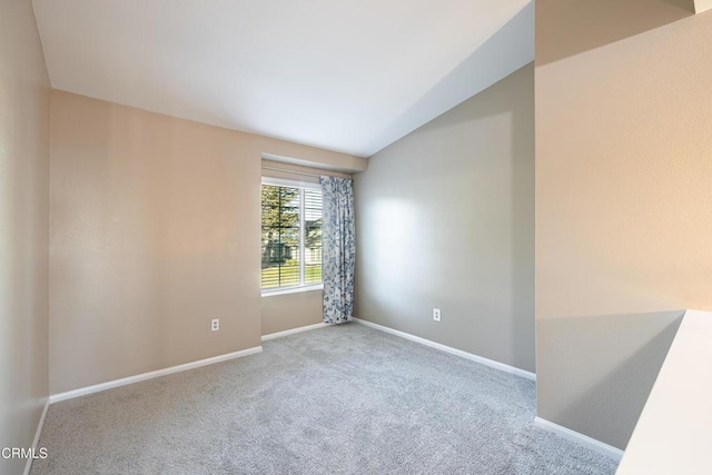 spare room with light carpet and vaulted ceiling