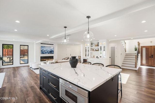 kitchen featuring pendant lighting, a center island, dark hardwood / wood-style floors, a breakfast bar area, and built in microwave