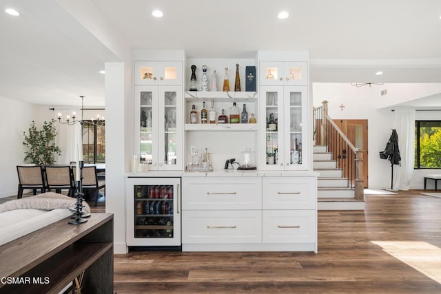 bar featuring dark wood-type flooring, white cabinetry, beverage cooler, and hanging light fixtures