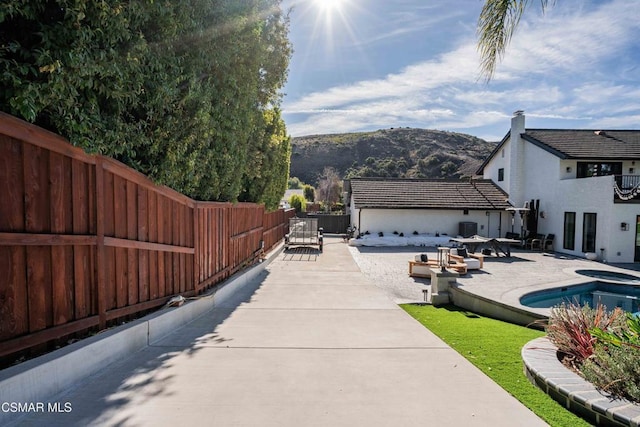 view of pool featuring a jacuzzi, a patio area, and a mountain view