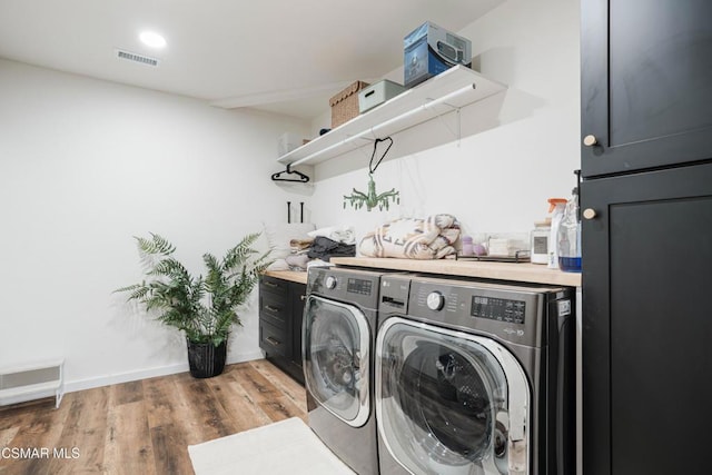 washroom featuring light wood-type flooring, washing machine and dryer, and cabinets