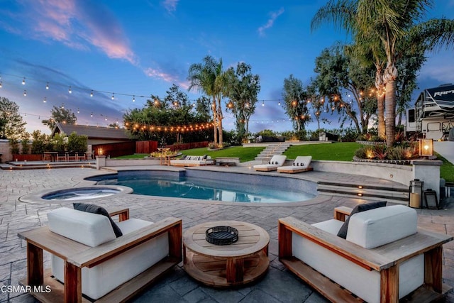 pool at dusk with a lawn, a patio area, and an in ground hot tub