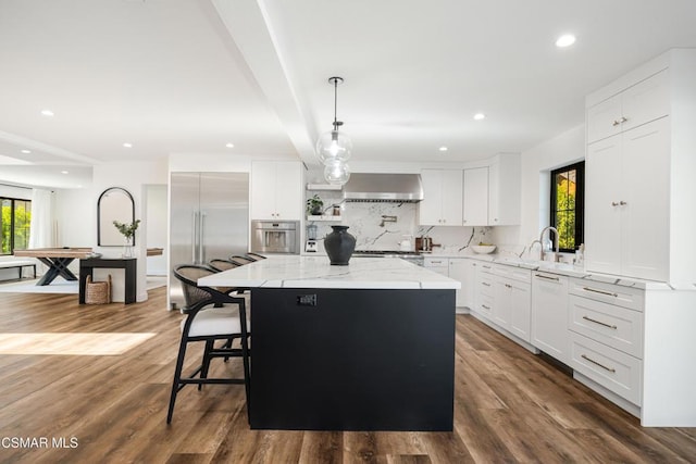 kitchen featuring white cabinets, wall chimney exhaust hood, and a kitchen island